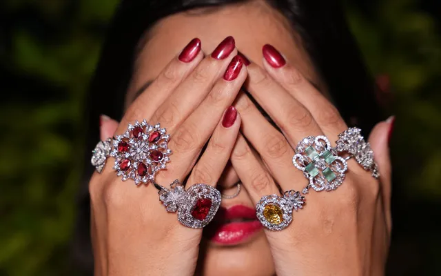 Five stone-set cocktail rings worn across both hands, with clean unstained skin around every band