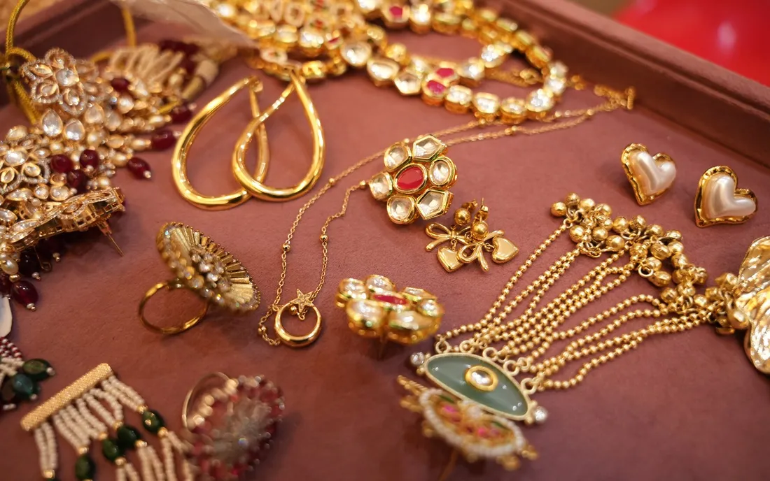A tray of jewellery essentials: gold-tone hoops, a thin chain with a pendant, pearl studs, cocktail rings and a kundan set
