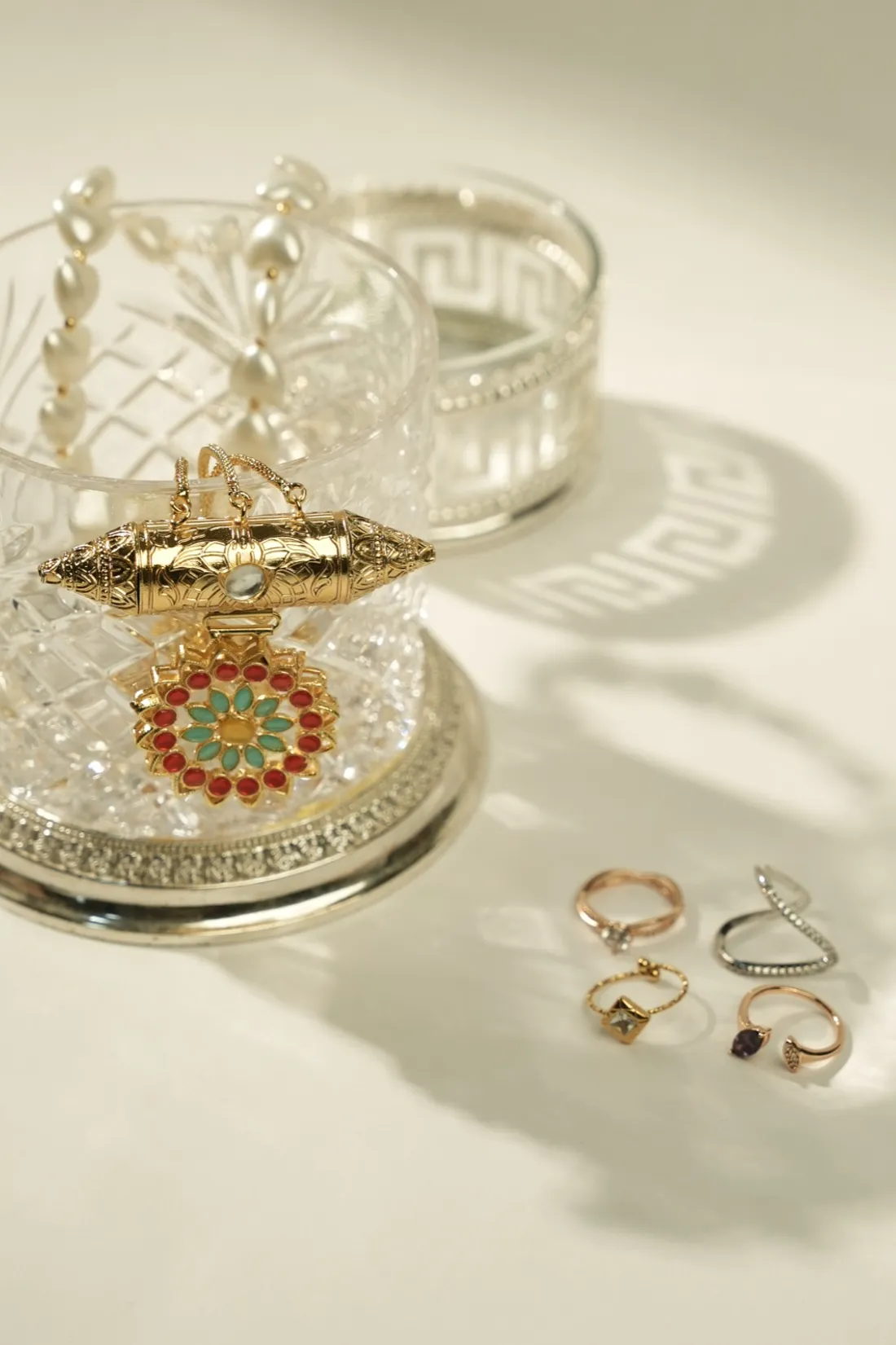 Gold-toned rings and stone-set bangles arranged on a mirrored tray