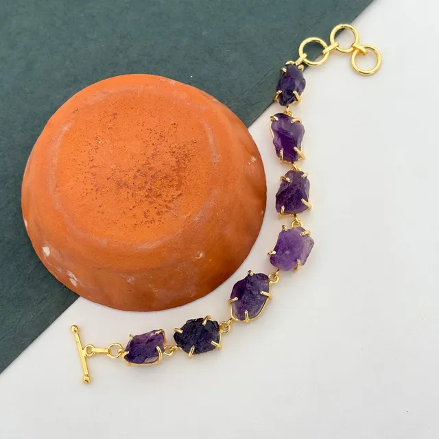 A rough stone bracelet of uncut amethyst crystals held in gold-tone prong settings, each stone a different shape
