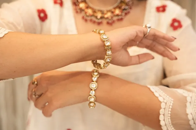 A kundan bracelet being tried on over a white kurta