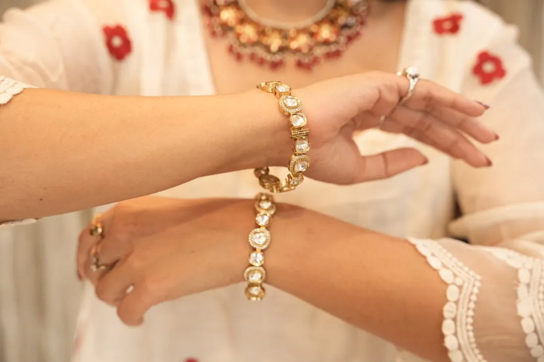 A kundan bracelet being tried on over a white kurta