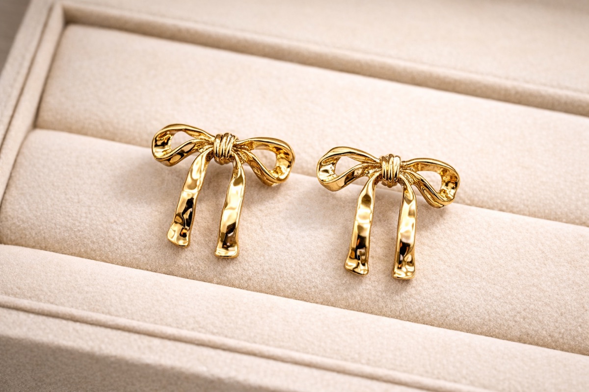 Gold bow stud earrings in a jewellery box