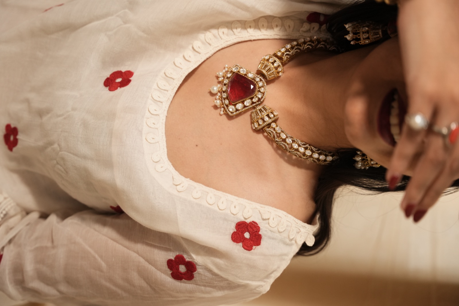 A red-and-gold necklace styled on a white kurta